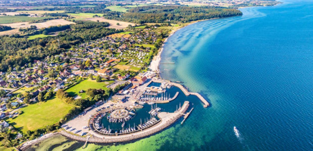 Dronebillede af Lundeborg havn, som er en marina med runde former og med en lille landsby tæt ved